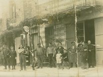 Maison Gilles et Brasserie Gautier, Charles et Emma Gilles, René Gilles et leur fils, Monsieur Gautier, Louis Malby et Ester Malby née Gautier, la Mémé Linon avec peut-être un petit fils. A vélo, Jacques et peut-être sa soeur Photo d'un groupe de personnes devant un commerce