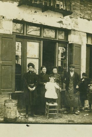 Épicerie Gilles, Charles et Emma Gilles avec la petite Marie-Louise sur la chaise Photo d'un groupe de personnes devant un commerce